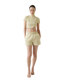 Woman wearing a light green outfit with a top and shorts on a white background